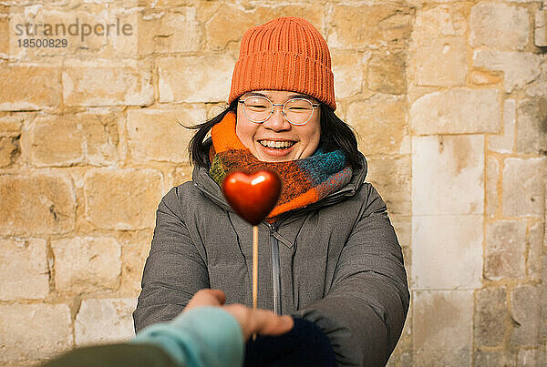 Asiatische Frau erhält glücklich ein rotes Herz zum Valentinstag