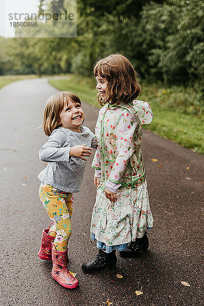 Zwei junge Mädchen spielen und lachen an einem Herbstmorgen entlang des Wanderwegs