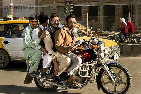 Vier Männer fahren während der morgendlichen Hauptverkehrszeit in Kabul Motorrad.