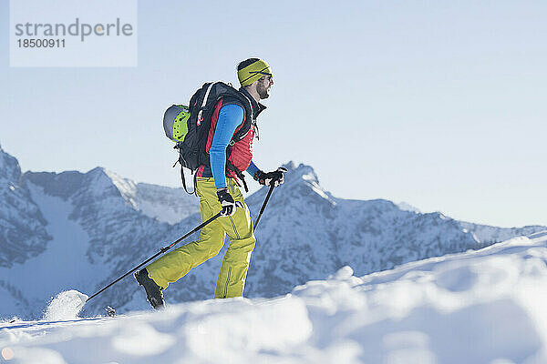Skifahrer klettert auf schneebedeckten Berg