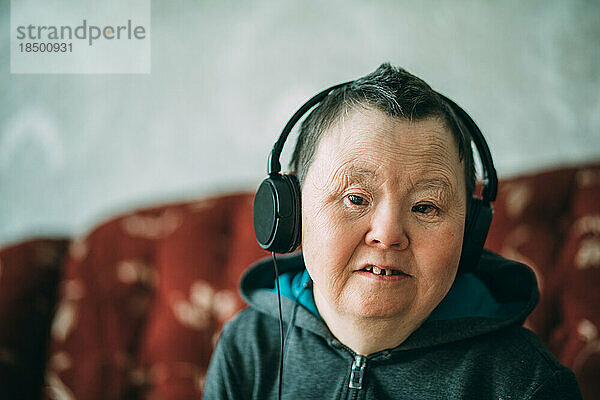 Ältere Frau mit Down-Syndrom trägt Kopfhörer und Musik