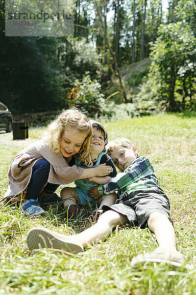 Nahaufnahme von drei kleinen Kindern  die sich an einem Sommertag umarmen