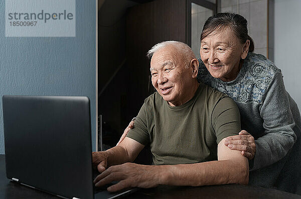 Älteres Paar zu Hause nutzt Laptop für Bildung oder Online-Einkäufe
