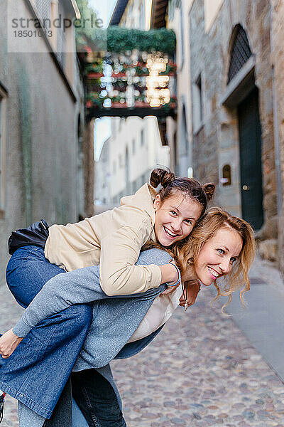 Eine blonde Frau und eine Tochter im Teenageralter gehen durch eine Altstadt spazieren