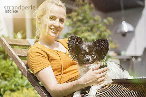 Porträt einer jungen Frau  die mit ihrem Hund im heimischen Garten sitzt  München  Bayern  Deutschland