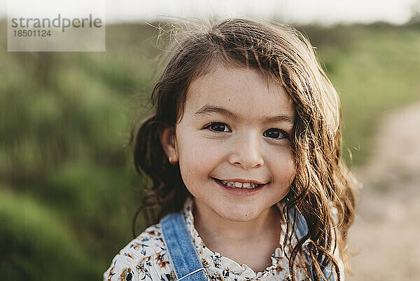 Porträt eines jungen Mädchens im schulpflichtigen Alter mit braunen Augen  das in die Kamera lächelt