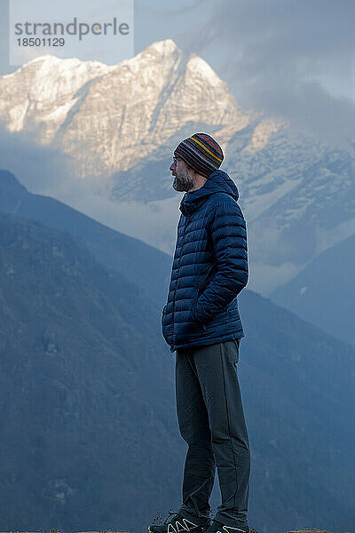 Ein bärtiger Mann blickt in der Abenddämmerung auf die Gipfel des Himalaya.