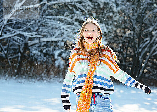 Glückliches Teenager-Mädchen mit gelbem Schal draußen im Schnee.