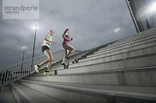 Zwei Frauen joggen im Morgengrauen auf Treppen  Bayern  Deutschland