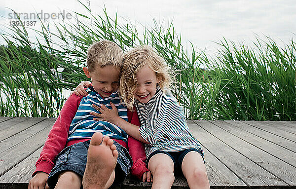 Bruder und Schwester umarmen und lachen im Sommer am Strand
