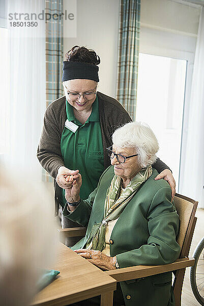 Pflegepersonal kümmert sich um ältere Frau im Altersheim