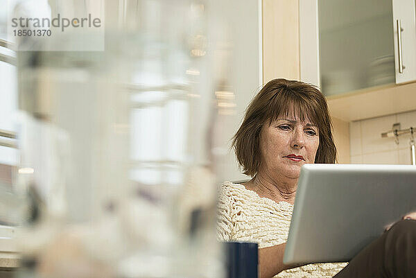 Ältere Frau nutzt ein digitales Tablet in der Küche  München  Bayern  Deutschland