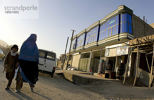 Frau in Burka geht an einem neu errichteten Gebäude in Kabul vorbei.