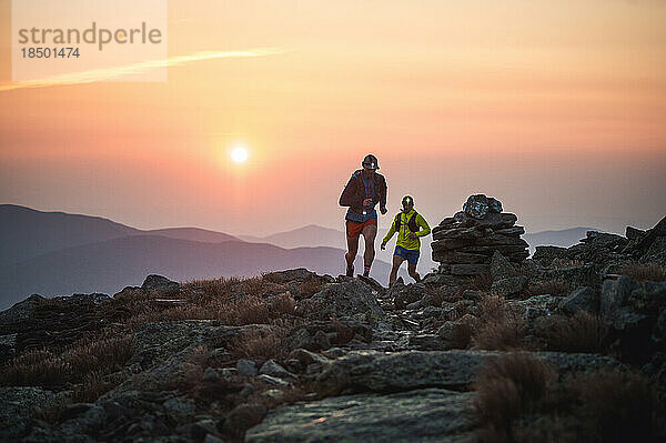 Silhouette männlicher Trailrunner  die bei Sonnenaufgang auf einem felsigen Pfad laufen