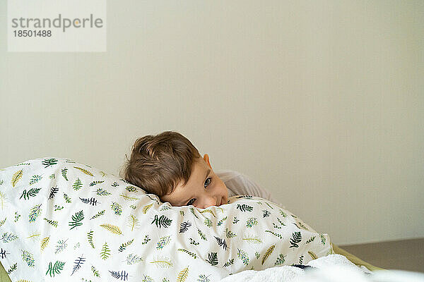 Glücklicher kleiner Junge im Schlafanzug  im Bett im Schlafzimmer mit to
