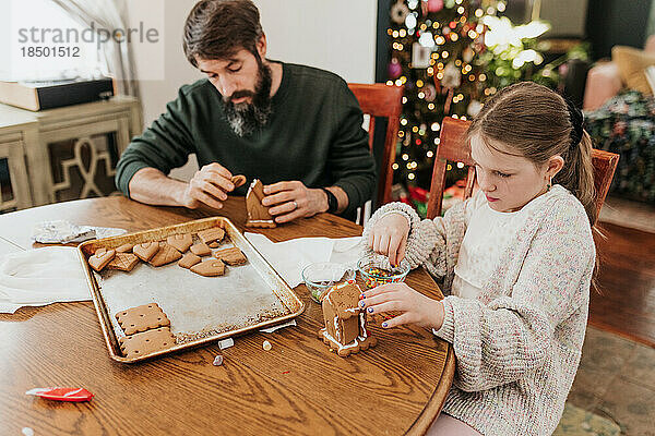 Vater und Tochter bauen gemeinsam ein Lebkuchenhaus