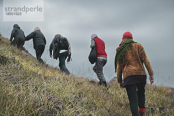 Eine Gruppe von Freunden wandert den steilen  wilden Berghang in Schottland hinauf