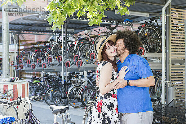 Junges Paar küsst sich am Fahrradparkplatz