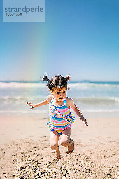 Asiatisches Mädchen springt am Strand
