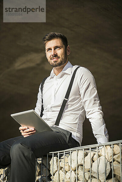 Geschäftsmann sitzt und arbeitet an einem digitalen Tablet  München  Bayern  Deutschland