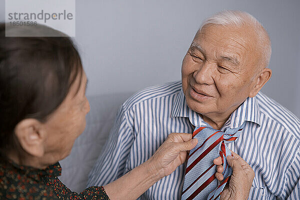 Ältere Frau bindet ihrem Mann die Krawatte