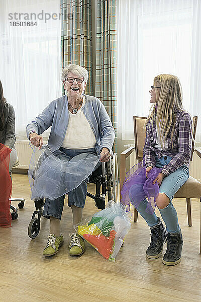 Mädchen und ältere Frau machen sanfte Sportübungen mit Stoff im Pflegeheim