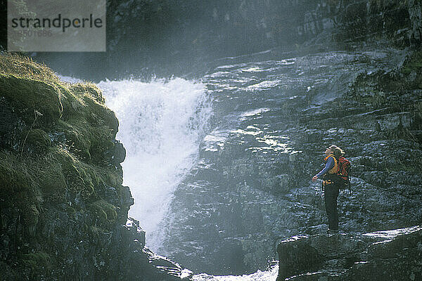 Eine Wanderin steht in der Nähe eines Wasserfalls.