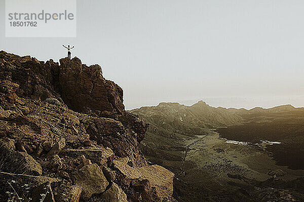 Zurückgezogen von einem Mann  der auf einem Felsen auf dem Berggipfel des Teide steht