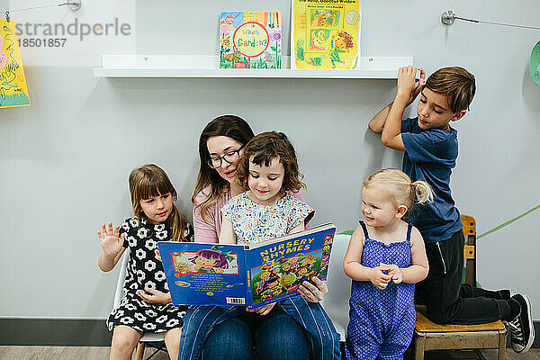Lehrer und vier Schüler lesen gemeinsam ein Buch