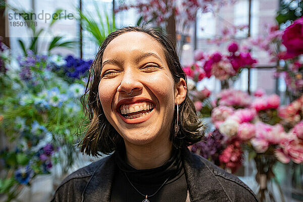 Lächelnde junge Frau im Floristen in Amsterdam und Blumen kaufen.
