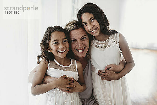 Porträt einer lächelnden Mutter und zweier Töchter im Studio mit natürlichem Licht