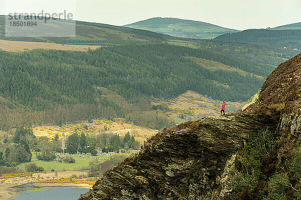 Frau auf dem Berggipfel  die den Blick auf den See in Glendalough bewundert