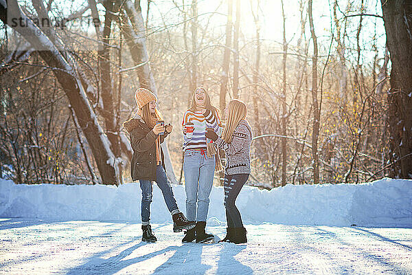Drei glückliche  schöne Teenager-Mädchen draußen im Schnee.