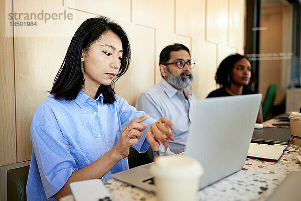 Geschäftsfrau überprüft die Zeit  während sie mit Laptop im Café sitzt