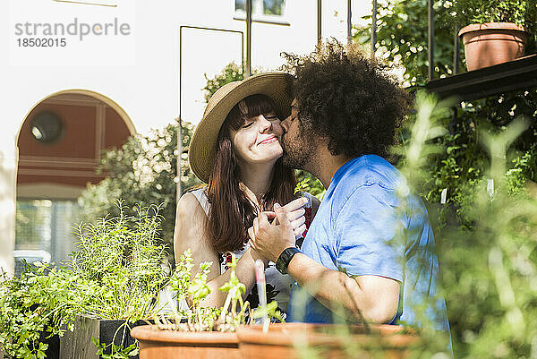 Junges Paar küsst sich im Kräutergarten