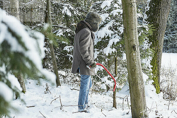 Junger Mann mit einer Säge im Wald im Winter  Bayern  Deutschland