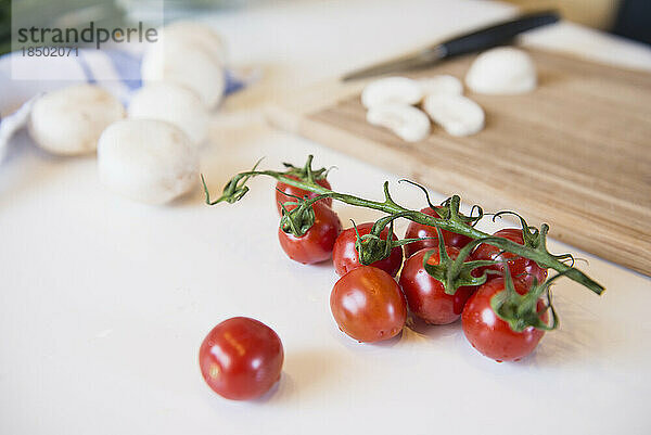 Tomaten  Pilze und Schneidebrett auf dem Küchentisch