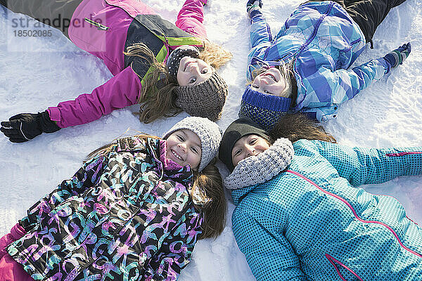 Porträt von Mädchen  die auf Schnee liegen