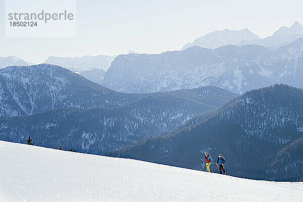 Skifahrer klettern auf Schnee gegen die Bergkette