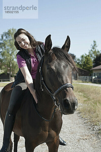 Reife Frau reitet auf einem Bauernhof und lächelt  Bayern  Deutschland