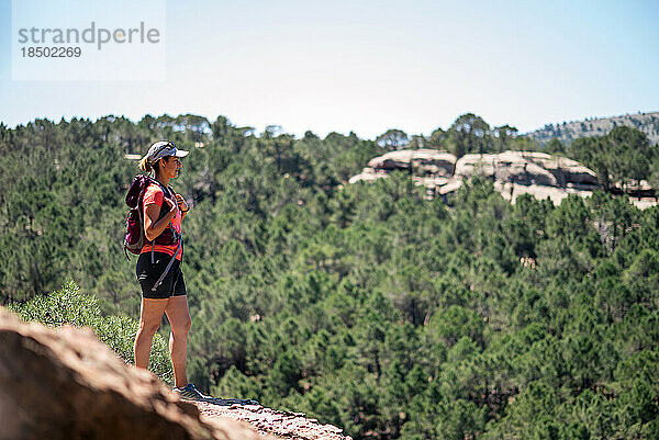 Wanderfrau mit Rucksack blickt von oben auf die Landschaft.