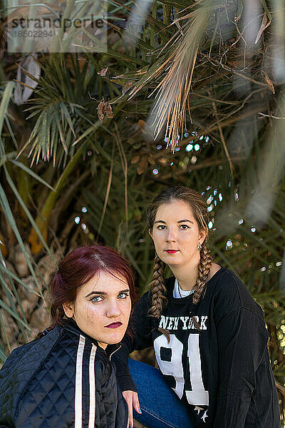 Zwei Frauen posieren mit Palmen im Hintergrund