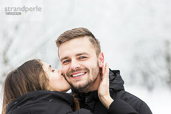 Mann und Mädchen umarmen sich im verschneiten Winterpark
