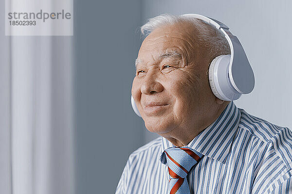 Ruhiger älterer Geschäftsmann  der Kopfhörer trägt und Audio hört