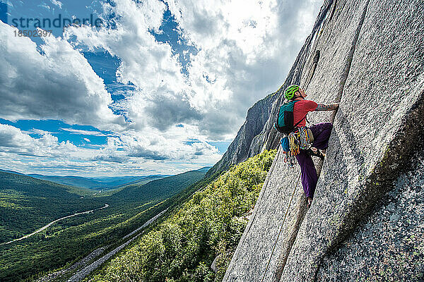 Mann klettert steilen Riss an der Felswand