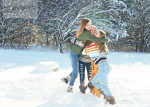 Drei kleine Mädchen spielen an einem Wintertag im Schnee.