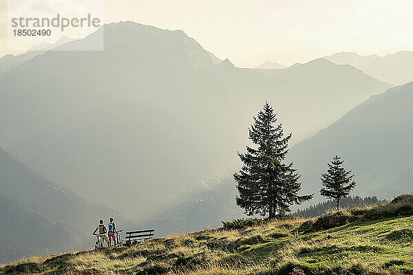 Ein paar Mountainbiker betrachten die Aussicht auf die alpine Landschaft  Zillertal  Tirol  Österreich