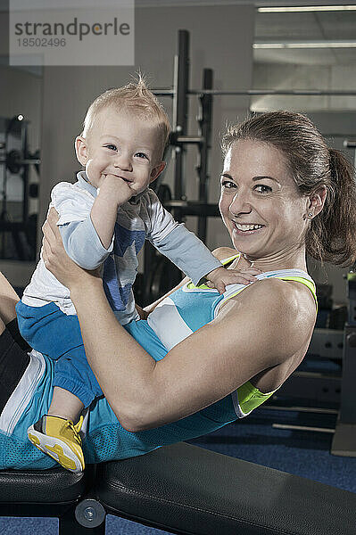Porträt einer lächelnden Mutter und ihres Sohnes im Fitnessstudio  Bayern  Deutschland
