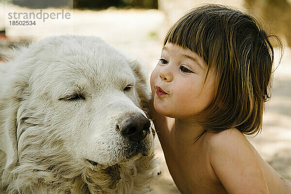 Süßes Kleinkind küsst liebevoll alten weißen Hund