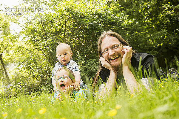 Glücklicher Vater und seine beiden Söhne liegen im Garten